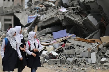 Palestinian students look at a building that was destroyed by Israeli air strikes near their damaged school in Gaza City May 7, 2019. Reuters