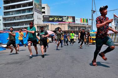 Anti-government protesters run for cover during skirmishes with shop owners near Baghdad’s Tahrir Square Tuesday, April 21, 2020. AP 