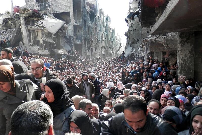 File photo released by the United Nations Relief and Works Agency for Palestine Refugees in the Near East (UNRWA) shows residents of the besieged Palestinian camp of Yarmouk, queuing to receive food supplies, in Damascus, Syria. There are reports the camp has fallen into the hands of ISIL. UNRWA/AP Photo