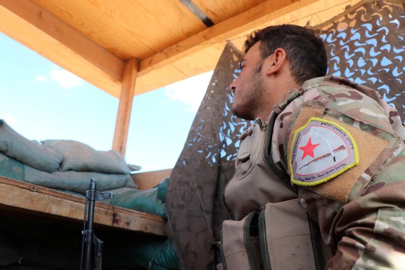 A fighter from the Syrian Democratic Forces, SDF, stands guard inside a post where U.S. troops were based, in Tal Abyad town, at the Syrian-Turkish border, Syria, Monday, Oct. 7, 2019. The SDF, a U.S.-backed Kurdish-led force accused Washington Monday of failing to abide by its commitments by withdrawing from northeast Syria ahead of a Turkish invasion that the Kurds say will overturn five years of achievements in the battle against the Islamic State group. (AP Photo)