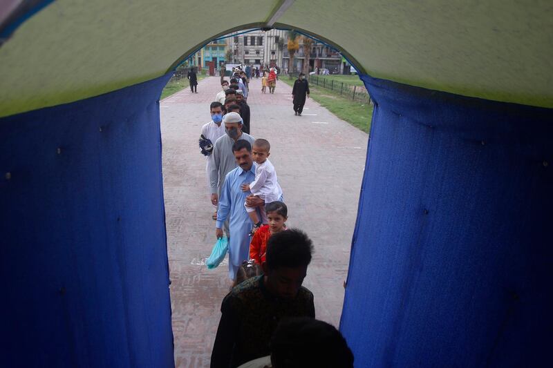 People walk through a sanitizer tunnel while entering the historical Badshahi Mosque to offer Eid al-Adha prayers, in Lahore, Pakistan, Saturday, Aug. 1, 2020. During Eid al-Adha, or Feast of Sacrifice, Muslims slaughter sheep or cattle and distribute portions of the meat to the poor. (AP Photo/K.M. Chaudary)