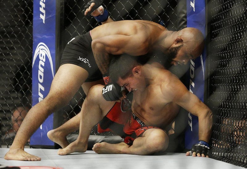 Demetrious Johnson, top, wrestles with Chris Cariaso during his successful flyweight title defence on Saturday night in Las Vegas. John Ocher / AP / September 27, 2014