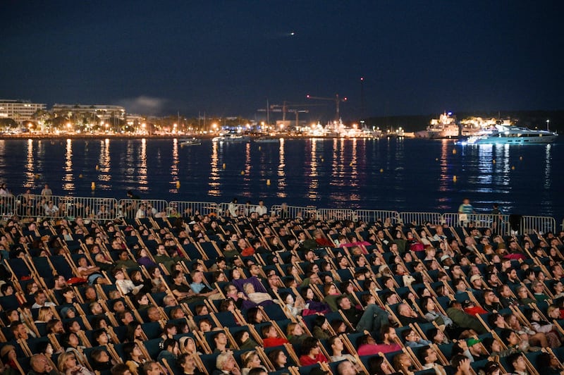 Spectators watch The Way of the Dragon at the "Cinema de la plage" at the 76th edition of the Cannes Film Festival. AFP
