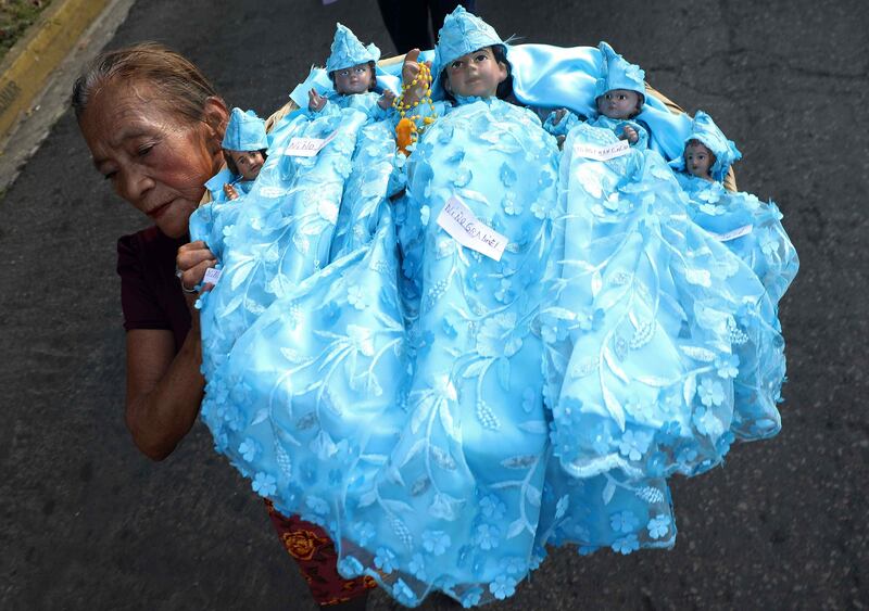 A woman carries figures of Baby Jesus during a procession for the Day of the Holy Innocents in Antiguo Cuscatlan, El Salvador. EPA
