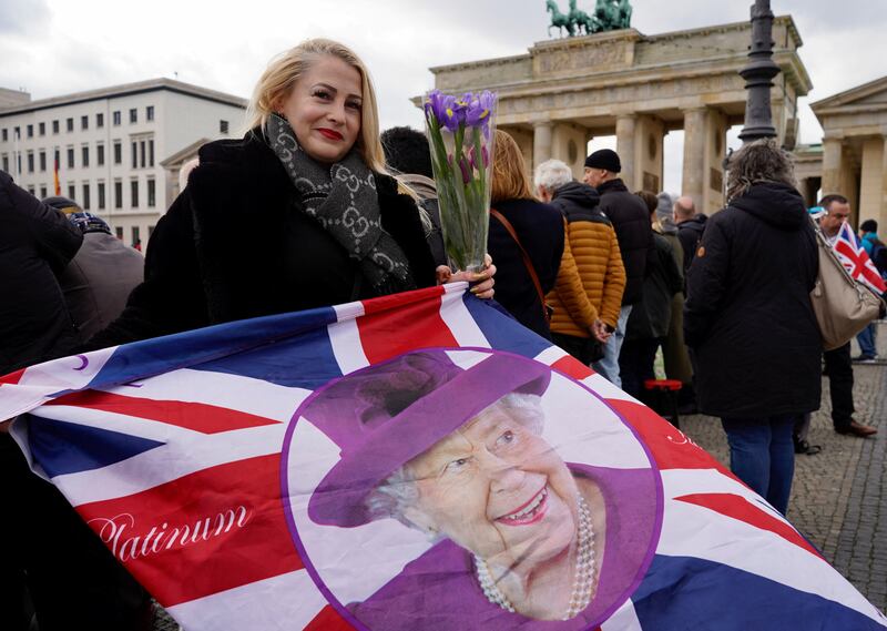 Ewa from Berlin holds a Union Jack flag with a picture of the late Queen Elizabeth II before the welcome ceremony for King Charles. Reuters