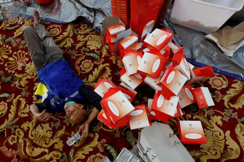A man is seen lying on the floor near of empty boxes that will be used to distribute food for free in Jakarta, Indonesia. Reuters
