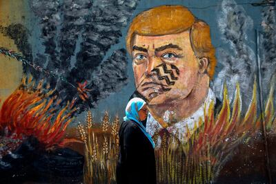 A Palestinian woman walks past a graffiti depicting US President Donald Trump with a footprint on his face in Gaza City on June 23, 2019. The United States is set to co-chair a two-day conference in Bahrain from June 25 focusing on the economic aspects of President Donald Trump's Israeli-Palestinian peace plan. The Palestinians confirmed in May they will not participate in the conference, adding they were not consulted beforehand. / AFP / MOHAMMED ABED
