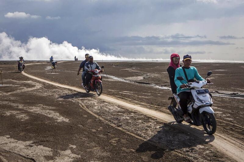 Visitors ride motorcycles over the mudflow during the tenth anniversary of the eruption. Ulet Ifansasti / Getty Images