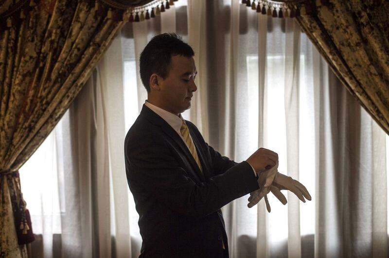 A butler in training puts on his gloves.