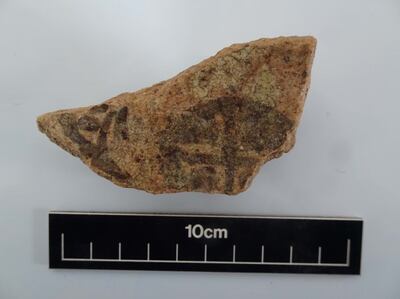 A small piece of pottery with the mark of a cross found at an excavation site in a cemetery in Bahrain. Photo: Bahrain Authority for Culture and Antiquities