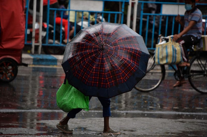 A boy takes shelter from rain under an umbrella in the north-east Indian city of Siliguri. AFP