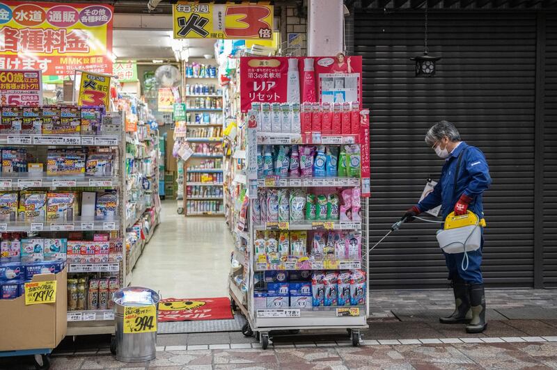 A volunteer sprays disinfectant to protect against the spread of Covid-19 coronavirus in a shopping arcade in Yokohama, Japan. Getty Images