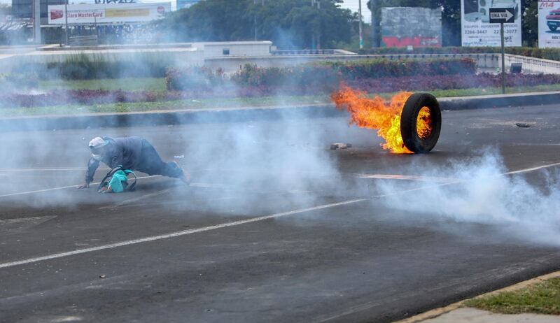 A masked protester slips after setting a tire on fire during a third day of violent clashes in Managua, Nicaragua. Alfredo Zuniga / AP Photo