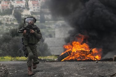 An Israeli soldier runs towards Palestinian demonstrators during clashes in the village of Kfar Qaddu, near the city of Nablus in the Israeli-occupied West Bank, on March 6, 2020. AFP
