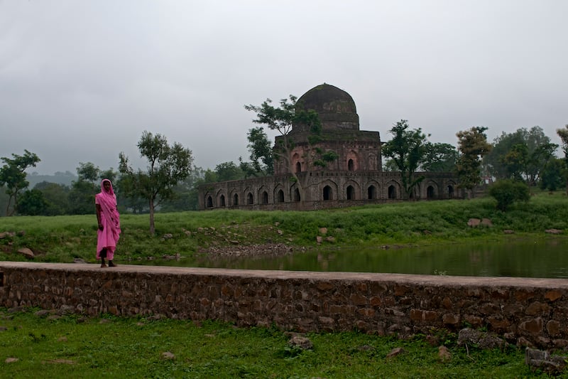 A local strolls past a deserted monument in Mandu