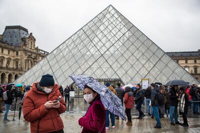 epa08264092 Visitors wearing protective masks outside the pyramid of the Louvre Museum as they wait for the decision of the staff meeting on the coronavirus outbreak in Paris, France, 02 March 2020. The famous museum held a staff meeting because the museum's employees and guards feared to be contaminated by visitors's flow over coronavirus epidemic COVID-19 disease.  EPA/CHRISTOPHE PETIT TESSON