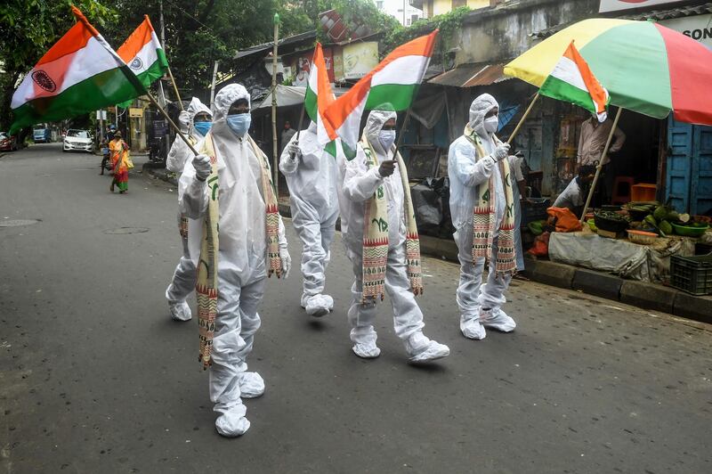 Frontline workers hold Indian national flags as part of the Independence Day celebrations in Kolkata. AFP