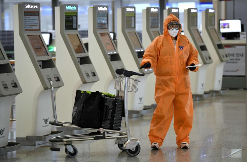 A passenger wearing protective clothing uses a self check-in machine at Incheon international airport, west of Seoul.  AFP