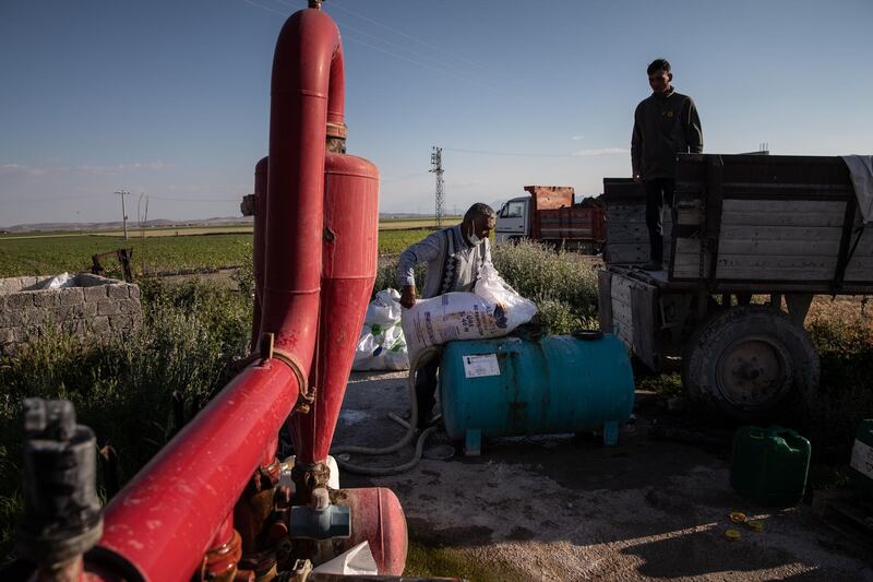 Farmers Hayri Kalkan, left, and  Niyazi Ibrahimi add fertiliser to extracted groundwater for irrigation. Drought and the depletion of groundwater has raised questions over whether agriculture is sustainable in parts of Konya.