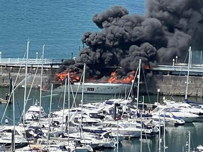 A photo from the Twitter feed of Tania Coatham shows flames and smoke rising from a superyacht which caught fire in Torquay marina on May 28, 2022.