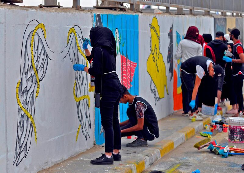 Iraqi fine arts students paint murals on a wall in the central Iraqi city of Hilla, south of the capital Baghdad.    AFP