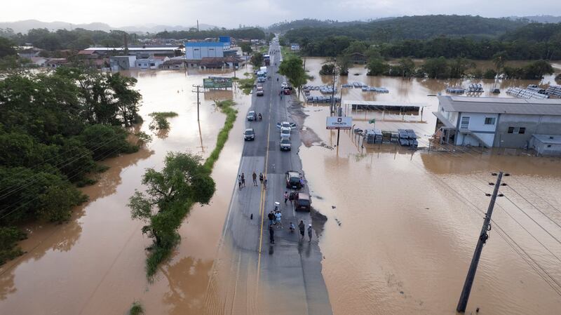 People gather on a road surrounded by flooding after heavy rain in Canelinha, in Santa Catarina state, Brazil. Reuters