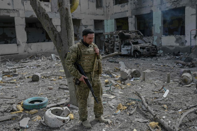 A Ukrainian soldier stands outside a school hit by Russian artillery in the village of Zelenyi Hai. AFP