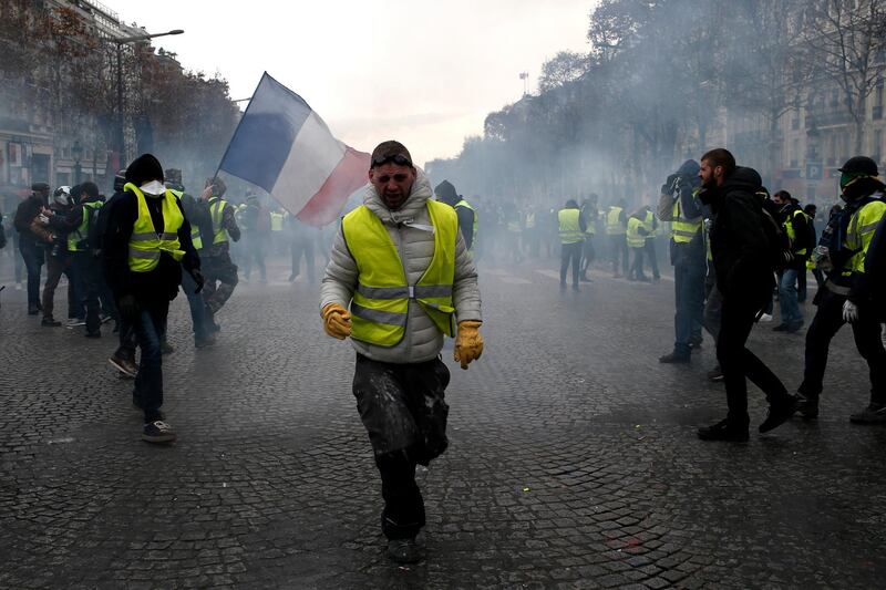 A demonstrator wearing a yellow vest grimaces through tear gas in Paris. AP Photo