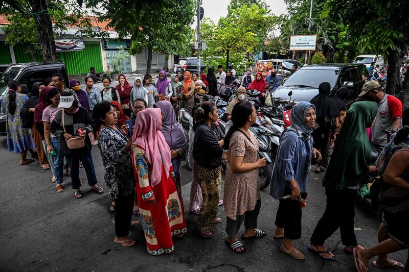 People queue in line to buy necessities at a government market event in Surabaya. AFP 