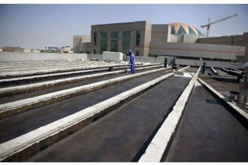 A worker waterproofs the roof of a new Abu Dhabi Judicial Department building last week, in preparation for the installation of 375 solar panels. Silvia Razgova / The National