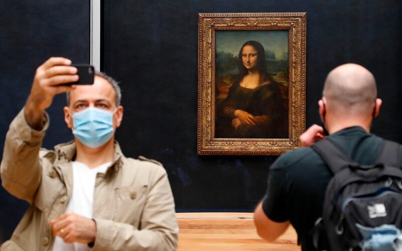 A visitor wearing a face mask takes a selfie in front of Leonardo da Vinci's masterpiece 'Mona Lisa' also known as 'La Gioconda'  in the Salle des Etats at the Louvre Museum in Paris.  AFP