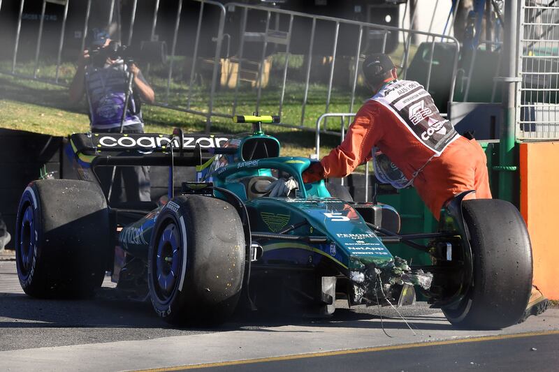 A race marshall clears Sebastian Vettel's Aston Martin off the track after a crash during the 2022 Formula One Australian Grand Prix. AFP