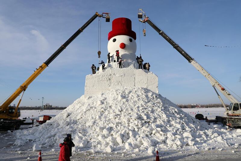 Cranes are seen next to workers sculpting a giant snowman by the Songhua River in Harbin, Heilongjiang province, China. Reuters