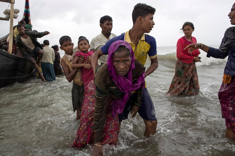 DAKHINPARA, BANGLADESH - SEPTEMBER 12:  A young Rohingya man carries an elderly woman, after the wooden boat they were travelling on from Myanmar, crashed into the shore and tipped everyone out on September 12, 2017 in Dakhinpara, Bangladesh. Recent reports have suggested that around 290,000 Rohingya have now fled Myanmar after violence erupted in Rakhine state. The 'Muslim insurgents of the Arakan Rohingya Salvation Army' have issued statement that indicates that they are to observe a cease fire, and have asked the Myanmar government to reciprocate.  (Photo by Dan Kitwood/Getty Images) *** BESTPIX ***