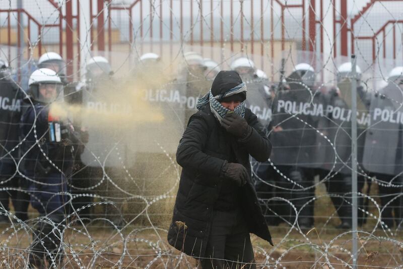 A Polish law enforcement officer uses tear gas, as migrants attempt to cross the border at a checkpoint in the Grodno region of Belarus. Reuters