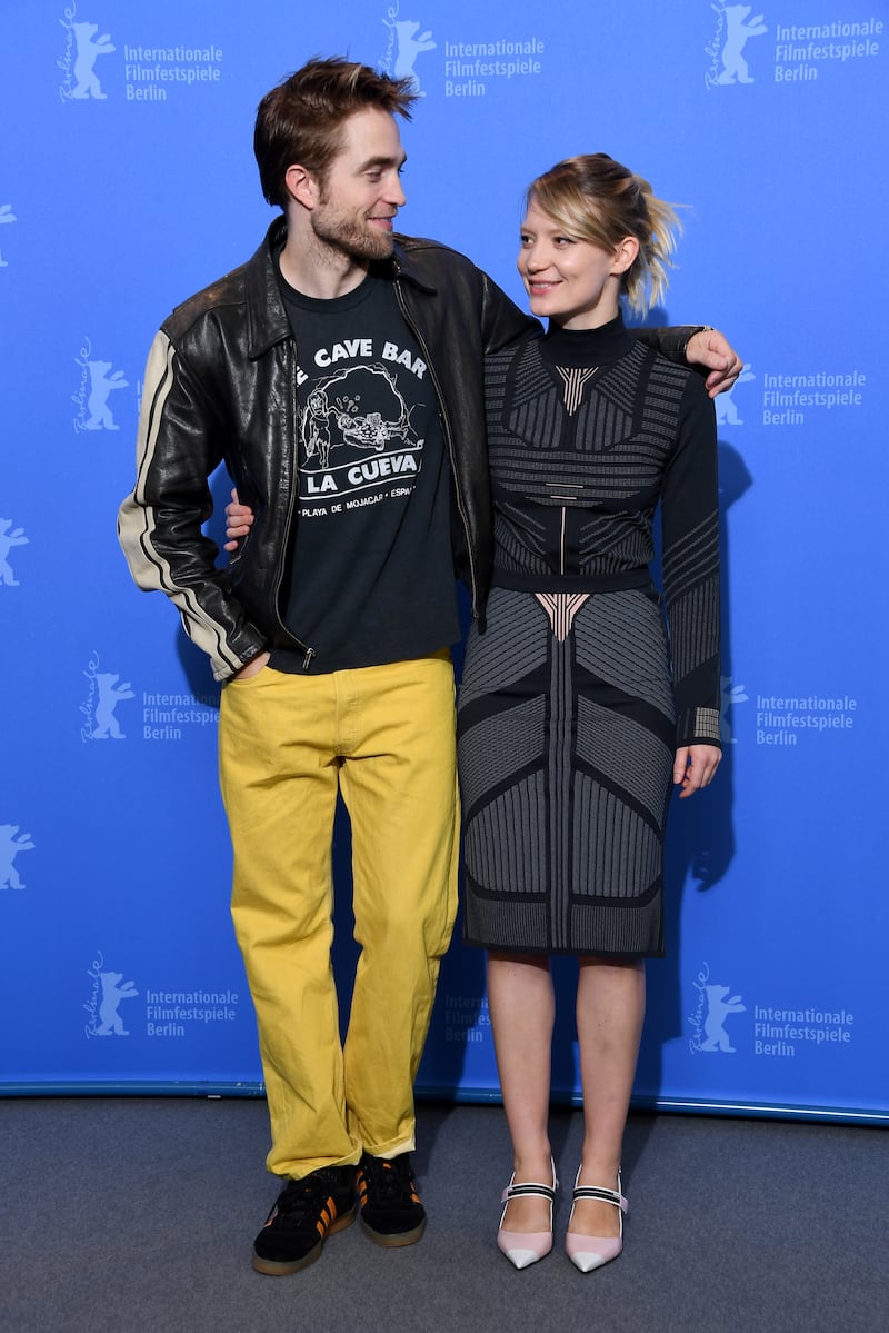 In a black leather jacket, logo T-shirt and yellow trousers, Robert Pattinson poses with Mia Wasikowska at the 'Damsel' photocall in Berlin on February 16, 2018. Getty Images