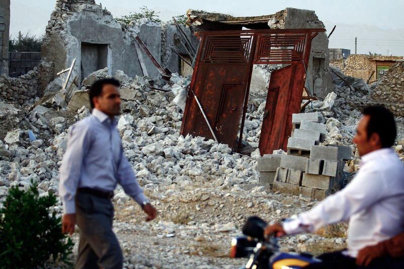 Iranians walk past the ruins of a destroyed house in the town of Shonbeh, southeast of Bushehr, on April 9, 2013 after a powerful earthquake struck near the Gulf port city of Bushehr. The 6.1 magnitude quake killed at least 30 people and injured 800 but Iran's only nuclear power plant was left intact, officials said.     AFP PHOTO/FARS NEWS/MOHAMMAD FATEMI
 *** Local Caption ***  875349-01-08.jpg