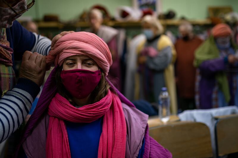 An actor wearing a face mask has their head piece adjusted before before a dress rehearsal for the Wintershall Estate's nativity play held in a barn on the estate in Guildford, Surrey. PA