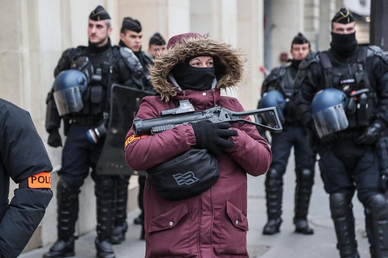 A French police officer holds a non-lethal weapon as she patrols in the center of Paris, during a demonstration called by "yellow vest" activists to protest against rising costs of living. AFP