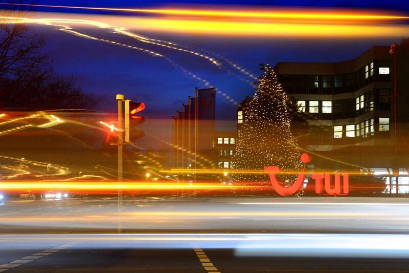 Cars drive past an illuminated logo of German travel and tourism giant TUI at the company's headquarters in Hanover, central Germany, on December 9, 2014. TUI presented its annual business report for 2013/14 on December 10, 2014. JULIAN STRATENSCHULTE / AFP