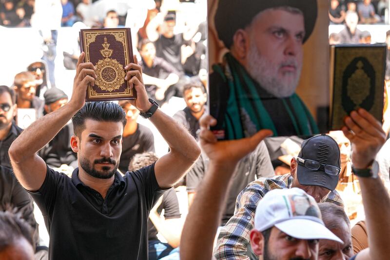A demonstrator holds up a portrait of Iraqi Shiite cleric Moqtada Al Sadr, in Kufa. AFP