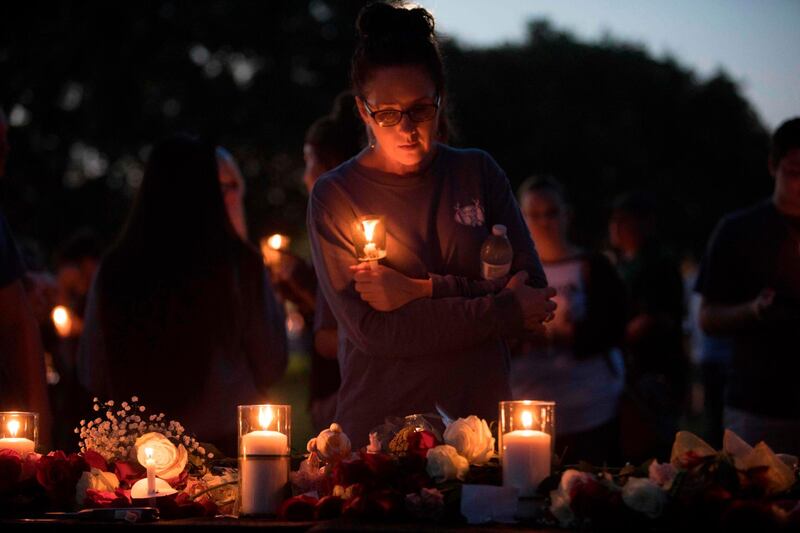 Catherine Casper sstands amid various momentos people have left during a candelight vigil in Santa Fe, Texas for the victims of the mass shooting on May 18, 2018.  Ten people, mostly students, were killed when a teenage classmate armed with a shotgun and a revolver opened fire in a Texas high school May 18, 2018, the latest deadly school shooting to hit the United States. The gunman, arrested on murder charges, was identified as Dimitrios Pagourtzis, a 17-year-old junior at Santa Fe High School. He is being held on capital murder charges, meaning he could face the death penalty.
 / AFP / Daniel KRAMER
