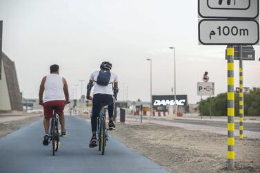 Two participants of the Rab3i Project, which pairs individuals with intellectual disabilities with volunteers sharing similar interests, go for a bike ride. The project is one of many initiatives in the UAE aimed at fostering inclusiveness for People of Determination. Antonie Robertson / The National