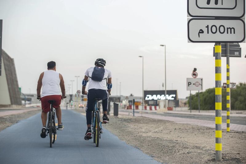 DUBAI, UNITED ARAB EMIRATES. 16 SEPTEMBER 2020. Shaddy Gaad (white vest) and his autistic buddy Omar Al Hashimi (Riding helmet) while cycling by the Creek in Business Bay. Since getting connected through the Rab3i platform which pairs people of determination with regular people who share their interested so they can have normal friends, they have been going out every 10 days to activities like cycling, swimming, playing video games and so on. (Photo: Antonie Robertson/The National) Journalist: Haneen Dajani. Section: National.