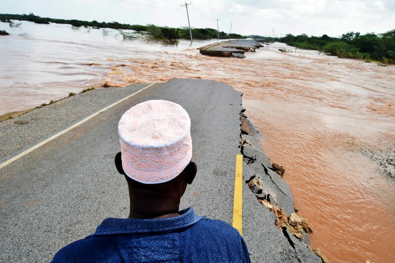 Members of the public view a section of the main Garsen-Lamu road that was swept away by heavy floods, in Gamba, Kenya. AP