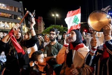 Protesters chant slogans, bang pot covers, and wave a Lebanese national flag during an anti-government demonstration in the southern Lebanon. AFP