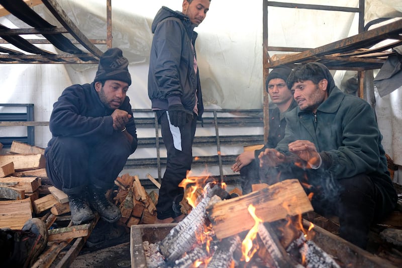 Migrants warm themselves around a fire. A fresh spate of snowy and very cold winter weather has brought more misery for hundreds of migrants. AP Photo
