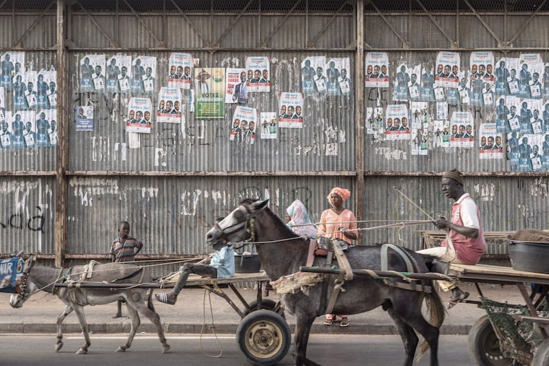 Carts pass electoral posters in Dhara, as 18 men and one woman compete to become Senegal's fifth president. AFP