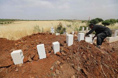 A man puts stones on the graves of five victims of a regime air strike on the village of Kafr Aweid in Idlib. AFP/Omar Haj Kadour