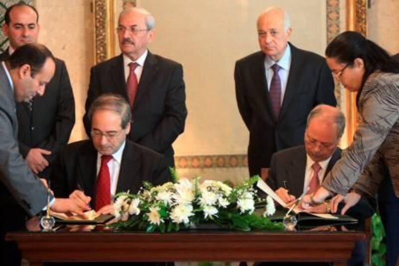 Syrian Deputy Foreign Minister Faisal Meqdad (L) and Arab League deputy secretary general Ahmed bin Hilly (R) sign an agreement during a meeting attended by Arab League Secretary General Nabil al-Arabi (back-R) at the institution's headquarters in Cairo on December 19, 2011 as Syria finally agreed to cooperate with Arab observers. AFP PHOTO / KHALED DESOUKI
 *** Local Caption ***  503570-01-08.jpg